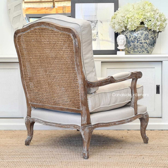 A stunning Clarke Armchair in weathered oak with a rattan back and cream upholstery, perfect for a Hamptons or coastal themed living room.