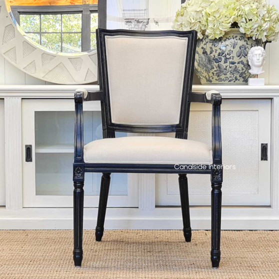 The Stark Carver Chair in distressed black with cream upholstery, a classical complement to your Canalside Interiors dining ensemble.