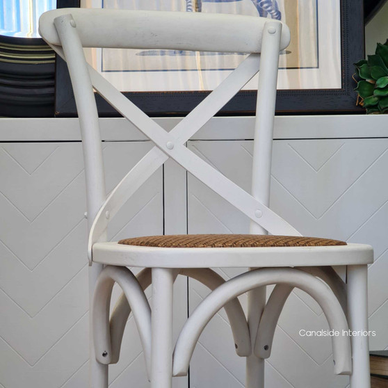 Canalside Interiors presents the Distressed White Cross Back Kitchen Stool, a Hamptons staple for a pristine dining room atmosphere