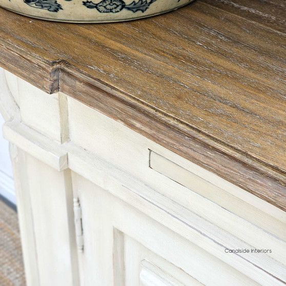 Canalside Interiors presents the Bastian Small Sideboard, blending a weathered oak top with a distressed stone finish, exemplifying classical Hamptons style.