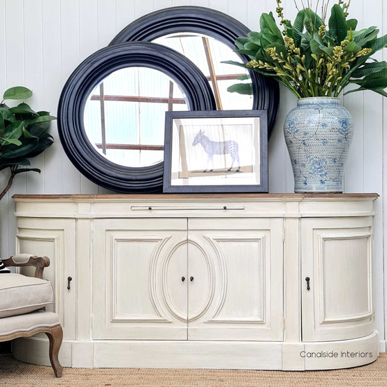The Bastian Large Sideboard's stone finish and weathered oak top blend traditional French design with a Hamptons-style flair, offering a sophisticated storage solution for your living room