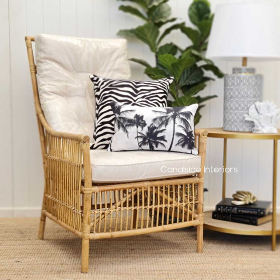 Raffles Cane Armchair in a modern Hamptons bedroom setting, featuring natural cane and cream cushions - Canalside Interiors