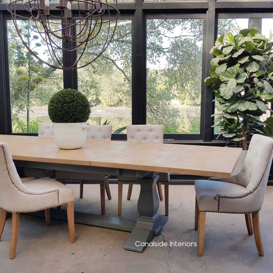 Front view of the Balmoral Parquetry Extension Dining Table set in a sunlit dining room, showcasing the natural parquetry top and the contrasting distressed grey base.
