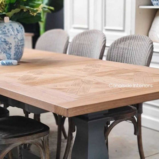 Front view of the Balmoral Parquetry Extension Dining Table set in a sunlit dining room, showcasing the natural parquetry top and the contrasting distressed grey base.