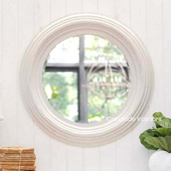 View of the Aspen Mirror at Canalside Interiors, showcasing its classic round design and distressed white finish.