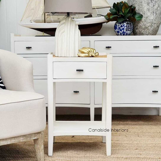 Showcasing the Tweed Hill Rattan Side Table/Bedside in distressed off-white, perfectly embodying coastal elegance in a sunlit bedroom.