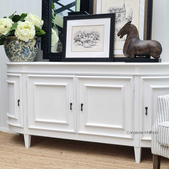 This Francia Curved 212cm Sideboard in distressed white from Canalside Interiors offers a seamless blend of Hamptons grace and modern functionality for your bedroom.