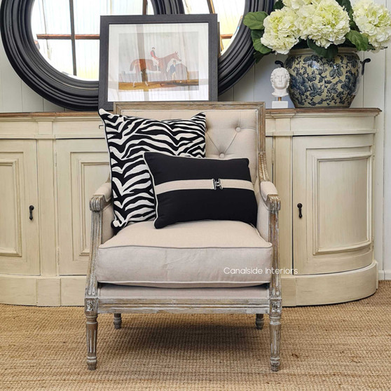 Side perspective highlighting the armchair's sleek lines and cream linen upholstery in a lounge room setting.