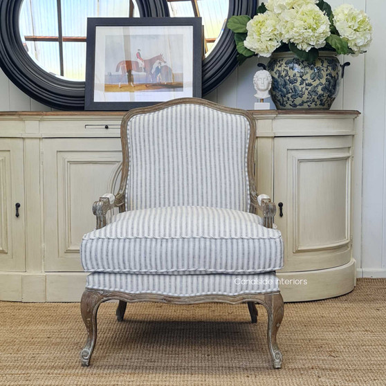 View of the Catelyn Armchair, featuring blue striped upholstery and weathered oak frame, styled in a Hamptons-inspired living room.