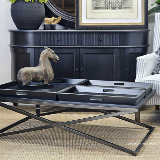 View of the Baxter Rectangular Coffee Table at Canalside Interiors, showcasing its distressed black finish and black metal base.