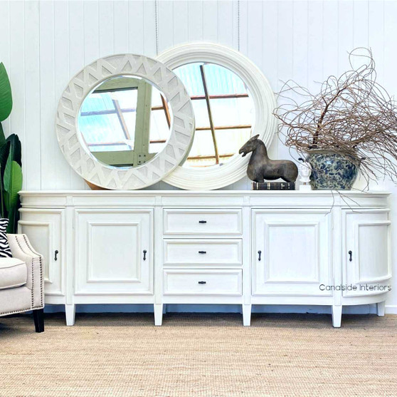 The Francia Grande Sideboard in distressed white commands attention in any living room, combining Canalside Interiors' craftsmanship with a Hamptons aesthetic