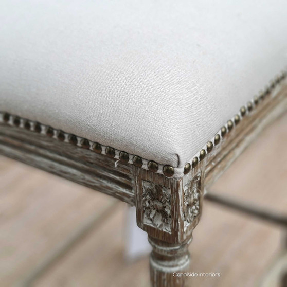 Elegantly crafted Caylee Kitchen Bar Stool with cream linen upholstery and weathered oak frame, adorned with brass studs, ideal for a Hamptons-style kitchen - Canalside Interiors