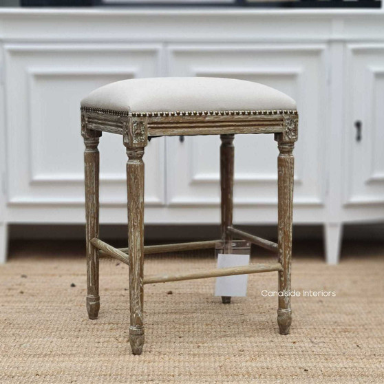 Elegantly crafted Caylee Kitchen Bar Stool with cream linen upholstery and weathered oak frame, adorned with brass studs, ideal for a Hamptons-style kitchen - Canalside Interiors