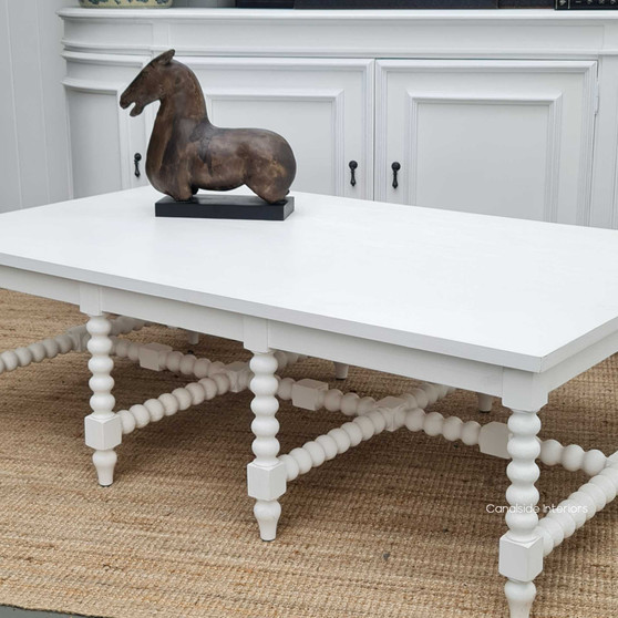 View of the Bobbin Coffee Table at Canalside Interiors, displaying its distressed brushed white finish and eight hand-turned bobbin legs.