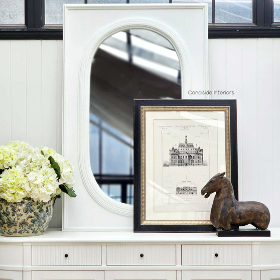 The hand-crafted Ovalis Mirror in distressed white adds a touch of sophistication to a Hamptons-style bedroom 
