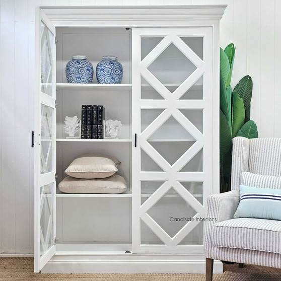 Front view of the Tunbridge Glass Display Cabinet in a Hamptons-style living room, displaying its distressed white finish and elegant cross door design by Canalside Interiors