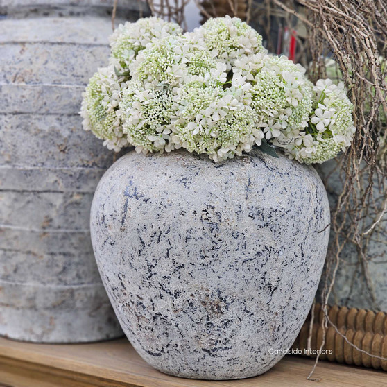 Full view of the Noema Terracotta Pot Vessel styled with white florals, showcasing its rounded form and textured stonewash finish.
