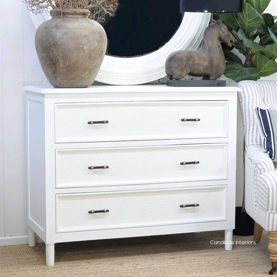 Angled view of the Brielle Rattan 3 Drawer Chest in White styled in a modern Hamptons home