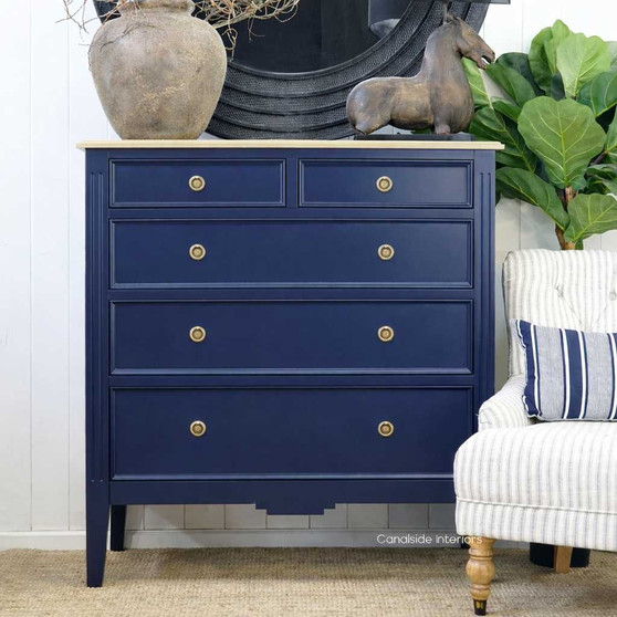 Angled view of the Navy Blue Peninsula 5 drawer chest with limewash top styled in a modern living space with decorative accents.