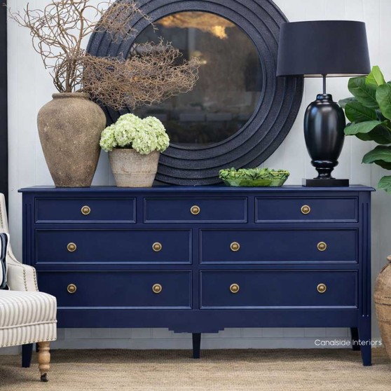 Front View of the Peninsula 7 Drawer chest in Navy styled with a round mirror and decorative ceramics, creating a polished Hamptons-inspired look.