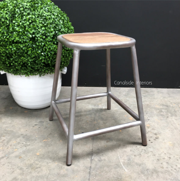 Front view of the Axis Industrial Low Stool, highlighting its wooden seat and metal base against a neutral background.