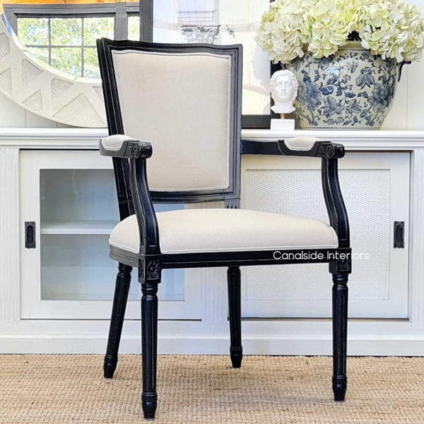 The Stark Carver Chair in distressed black with cream upholstery, a classical complement to your Canalside Interiors dining ensemble.