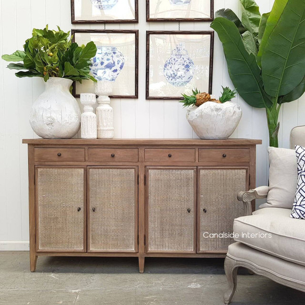 Frontal view of the Hayes Plantation Sideboard in weathered oak with rattan doors, set in a light-filled Hamptons-style dining room.