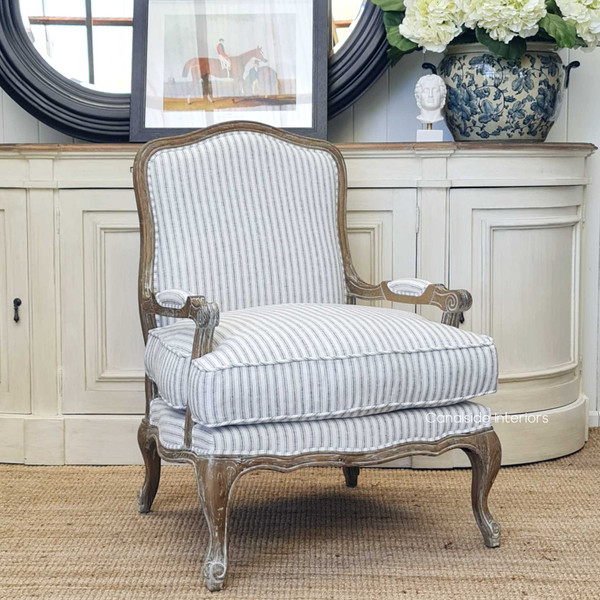 View of the Catelyn Armchair, featuring blue striped upholstery and weathered oak frame, styled in a Hamptons-inspired living room.