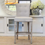 Frontal view of the Montague Upholstered Buttoned Back Kitchen Bar Stool, showcasing its cream upholstery and weathered oak legs, perfect for modern Hamptons-style kitchens - Canalside Interiors.