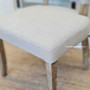 Detail shot of the Mimi Dining Chair's seat, emphasizing the comfort and quality of its cream upholstery.