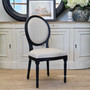 A modern dining room is graced by the sophisticated oval back and distressed finish of the Sansa Dining Chair