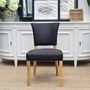 Frontal view of the Mimi Dining Chair in black/charcoal, set against the backdrop of a Hamptons-style dining room, highlighting its distressed natural legs and brass studs.