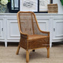 St Croix Rattan Dining Chair placed on a textured rug, highlighting the natural beauty and quality construction for a coastal bedroom setting.