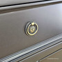 Close-up of the drawer knobs, revealing the aged brass finish and classic ring design.