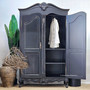 Styled shot of the James Armoire next to a potted plant, blending traditional form with organic styling.