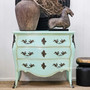 Wide shot of the aqua chest in a white-panelled room, creating a clean, coastal contrast.
