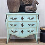 Front view of the Bretigny Commode Chest in distressed aqua, showcasing its bombe shape and ornate bronze hardware.