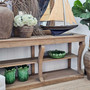 Console styled with a ship model and botanical branches, blending organic and nautical decor.