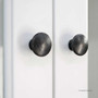 Close-up of the brass knobs on the upper doors, offering a refined contrast against the crisp white painted finish.