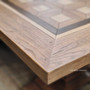 Artistic shot focusing on the Chambers Dining Table's edge, where the fine wood grains and parquetry inlay intersect.