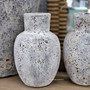 Decorative stonewash vessels styled against rustic textures, highlighting the contrast between natural materials and aged finishes.