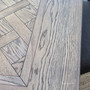 Close-up of parquetry grain pattern and intricate border inlays on the Berenson Cigar oak table.