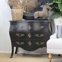 Wide shot of the distressed black chest in a white-panelled room, creating a clean, coastal contrast.