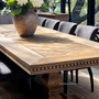 Luxurious dining space featuring extendable oak parquetry table and tufted upholstered chairs.