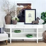Louis Curved Console Table White styled beside a striped armchair, highlighting its elegant curved end and shelving.