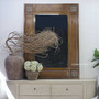 Centered frontal image showing the Oh Somh Mirror styled with rustic pottery and natural foliage.