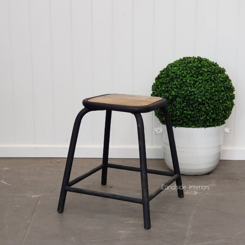 The Elementary Dining Height Stool in distressed black, showcasing its sleek design in a modern dining setting.