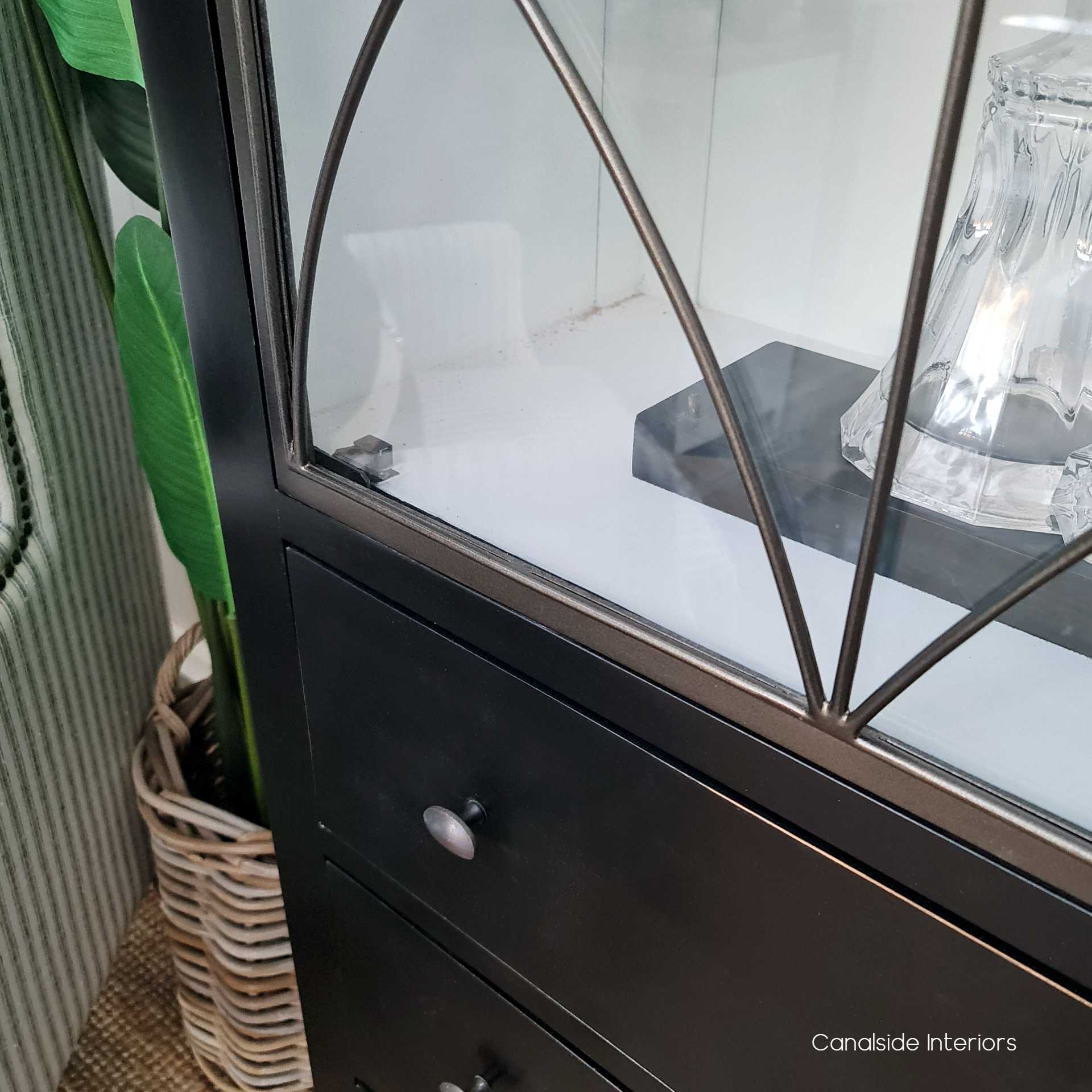 The cabinet's metal door captured under soft lighting, accentuating the delicate ironwork and the shadow play it creates.