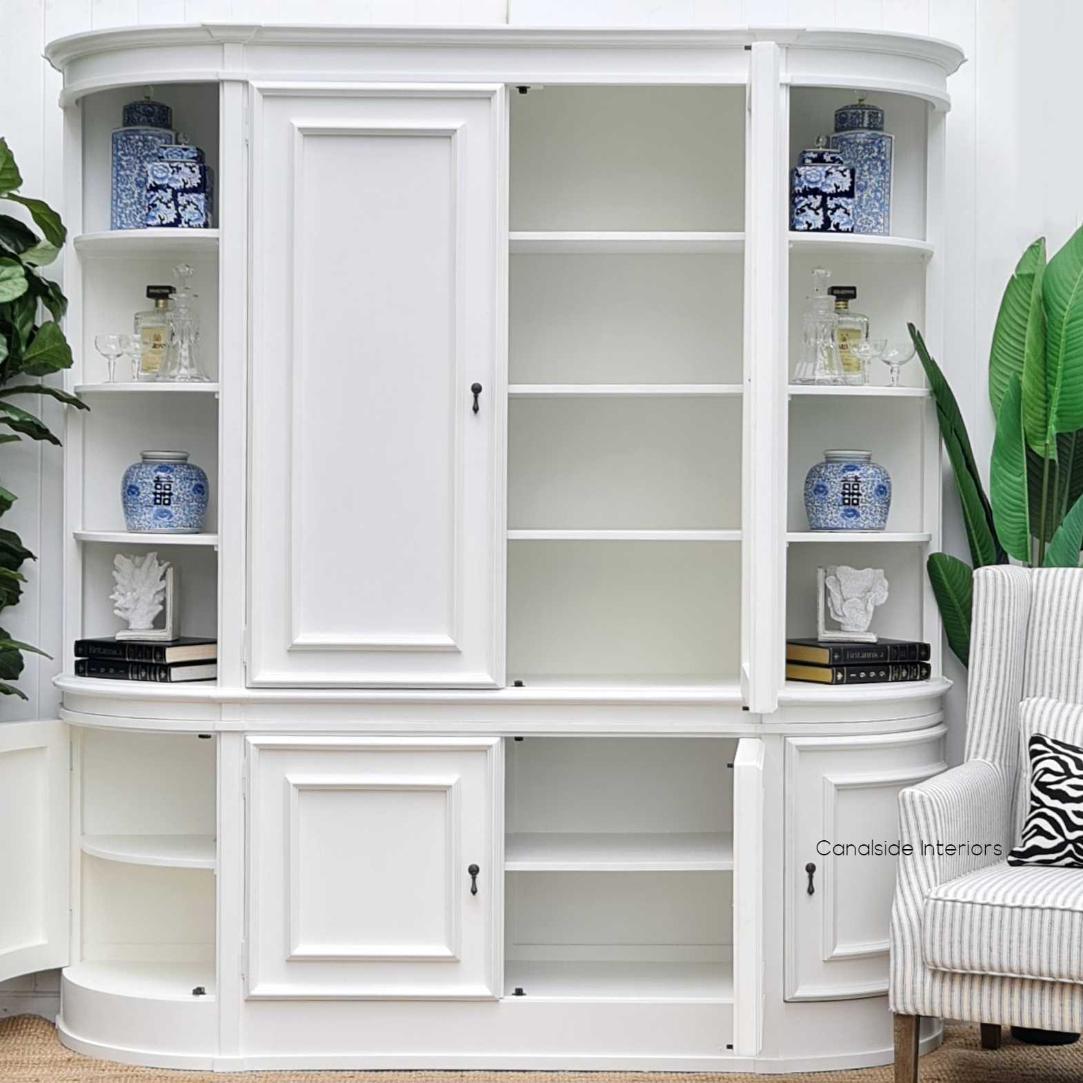 The Francia Curved Wall Unit adorned with books and ornaments, demonstrating how it can enhance the narrative of a room's design with its fixed shelving