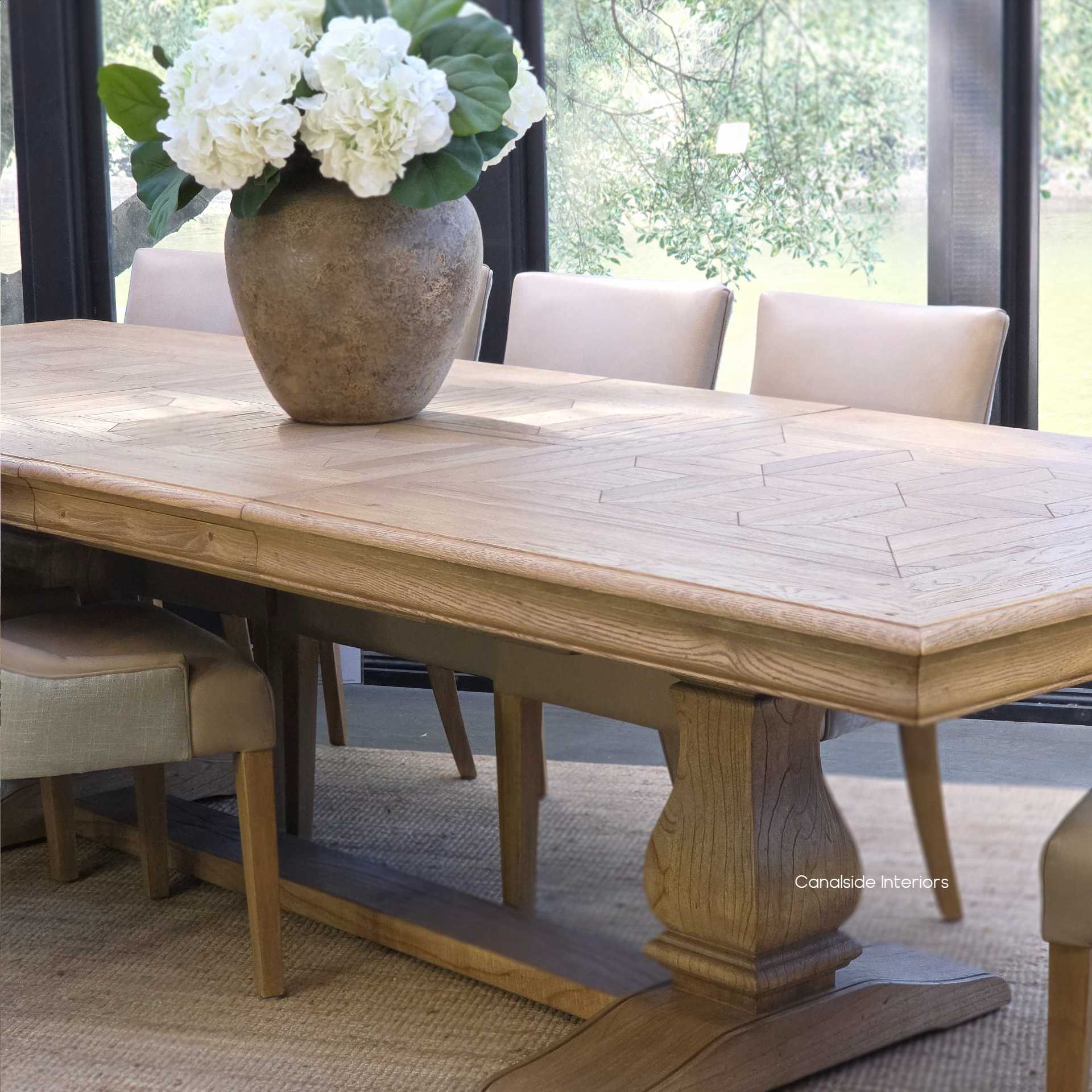 Front angled view of the Chesterton Oak Parquetry Double Extension Table displayed with leather dining chairs